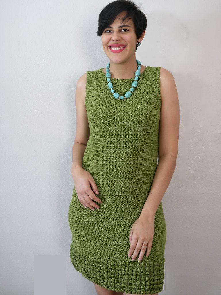smiling woman in a pixie cut wearing a green crochet shift dress