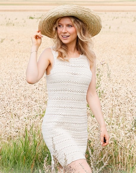 woman wearing a straw hat and crochet dress in a field