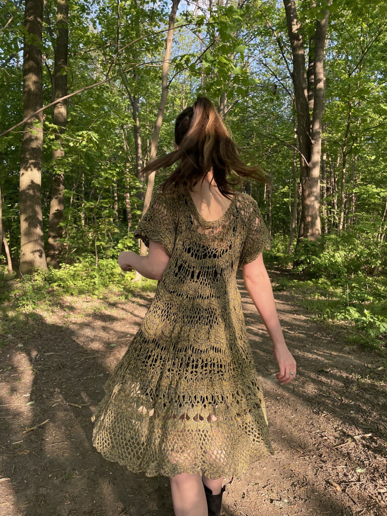 back of a woman wearing a crochet dress in forest trail