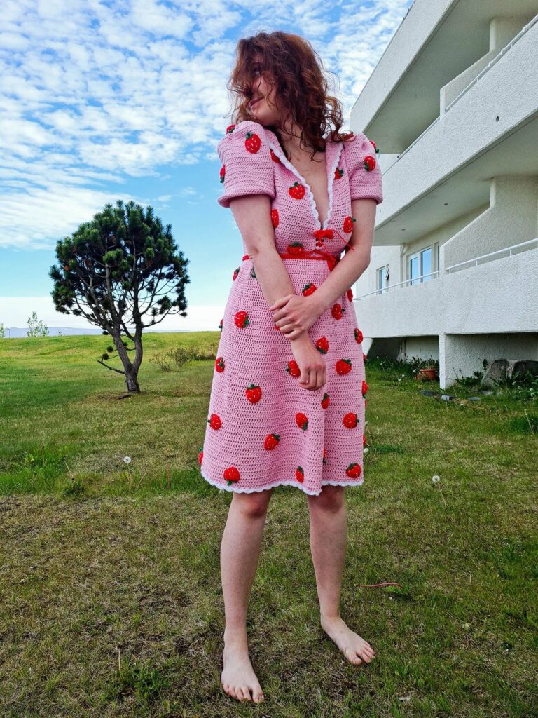 barefooted woman wearing a pink crochet dress with strawberry details