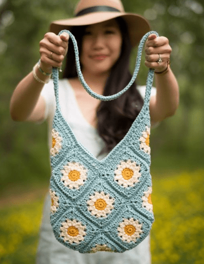 A woman holding the Summer Days Daisy Crochet Bag