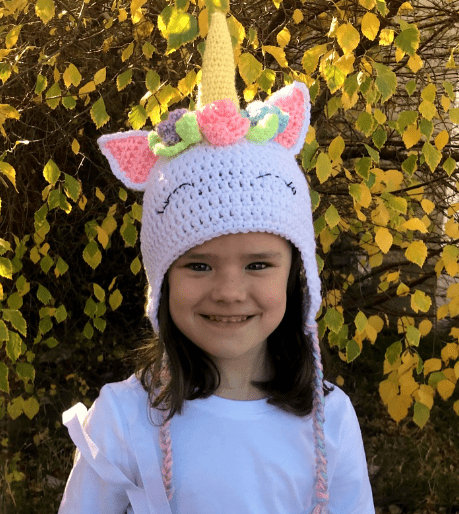A girl wearing a Crocheted Unicorn Hat with Flowers